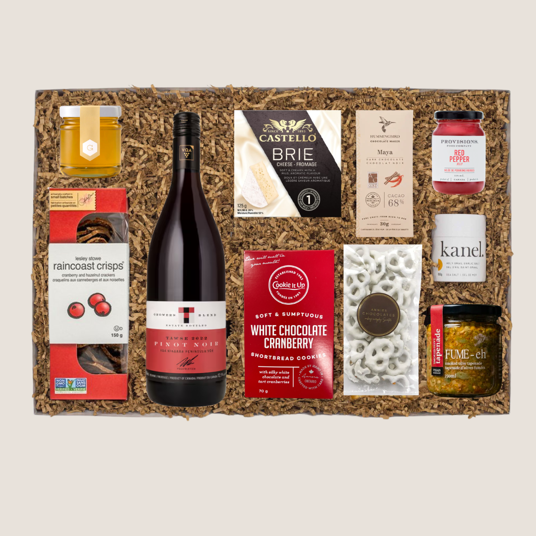 A gourmet charcuterie gift basket with Canadian-made wine and gourmet snacks including crackers, honey, brie, olive tapenade, red pepper jelly etc.